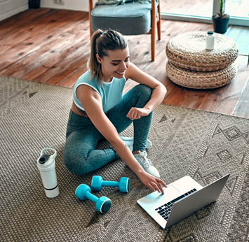 Woman sitting with laptop and workout gear