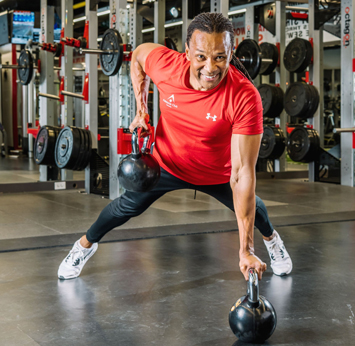 Garth using kettlebells wearing a red Adelaide Club branded t-shirt