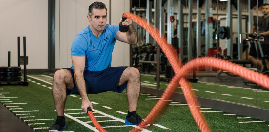 Member wearing blue Adelaide Club branded t-shirt using the battle ropes