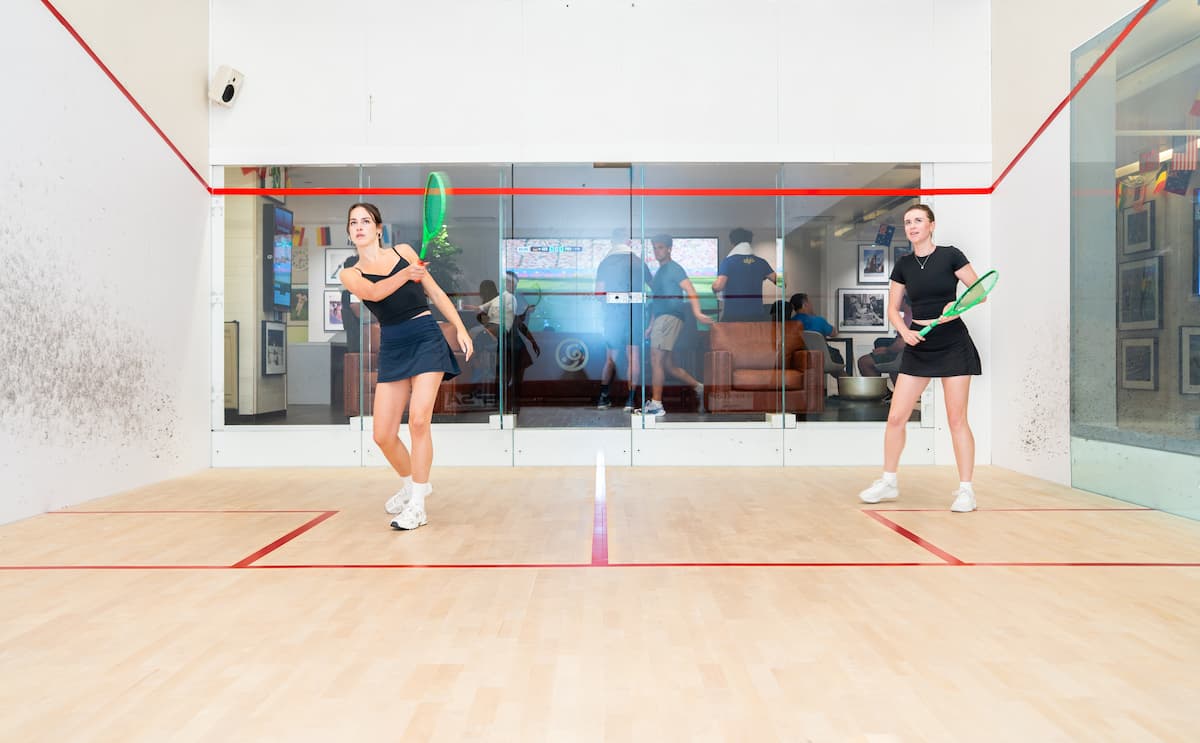 Two women mid-rally on a squash court at the Adelaide Club