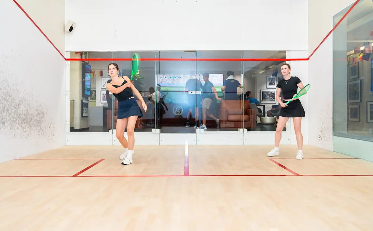 Two women mid-rally on a squash court at the Adelaide Club