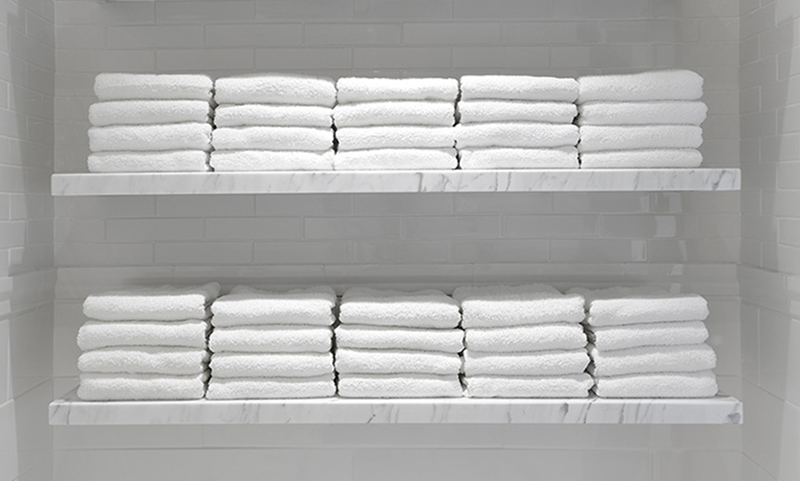Stacks of fresh white towels neatly folded on marble shelves inside the Adelaide Club locker room