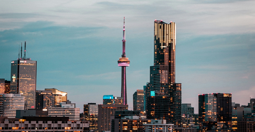 The Toronto skyline at dusk with the CN Tower and surrounding high-rise buildings.