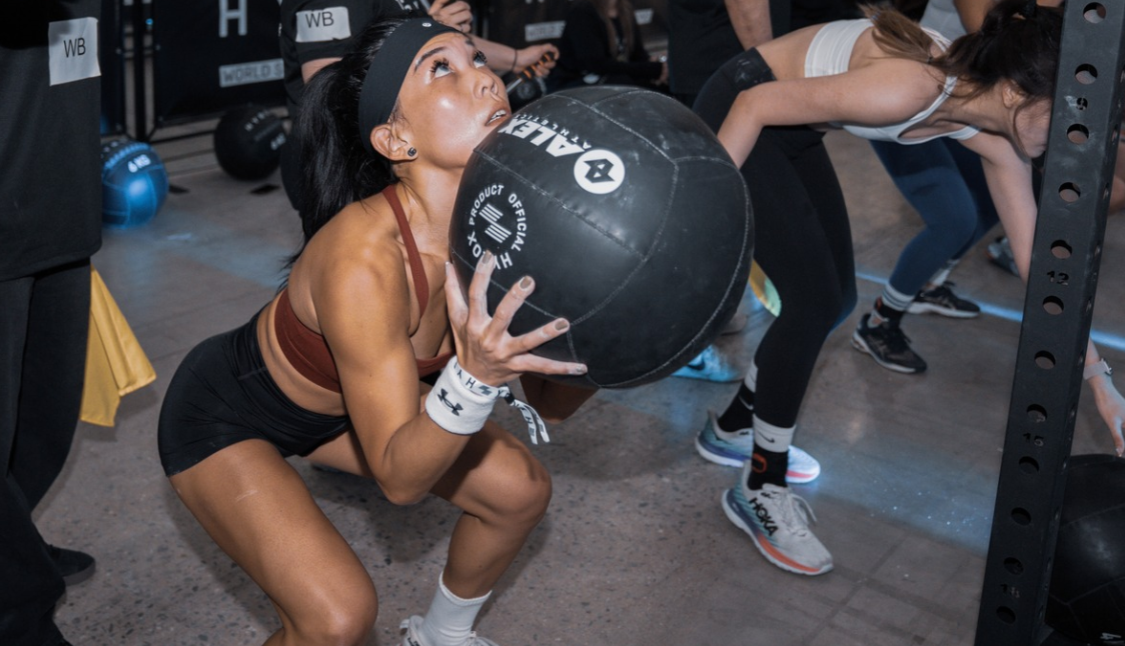 Participant performing HYROX wall ball repetitions during a functional fitness competition.