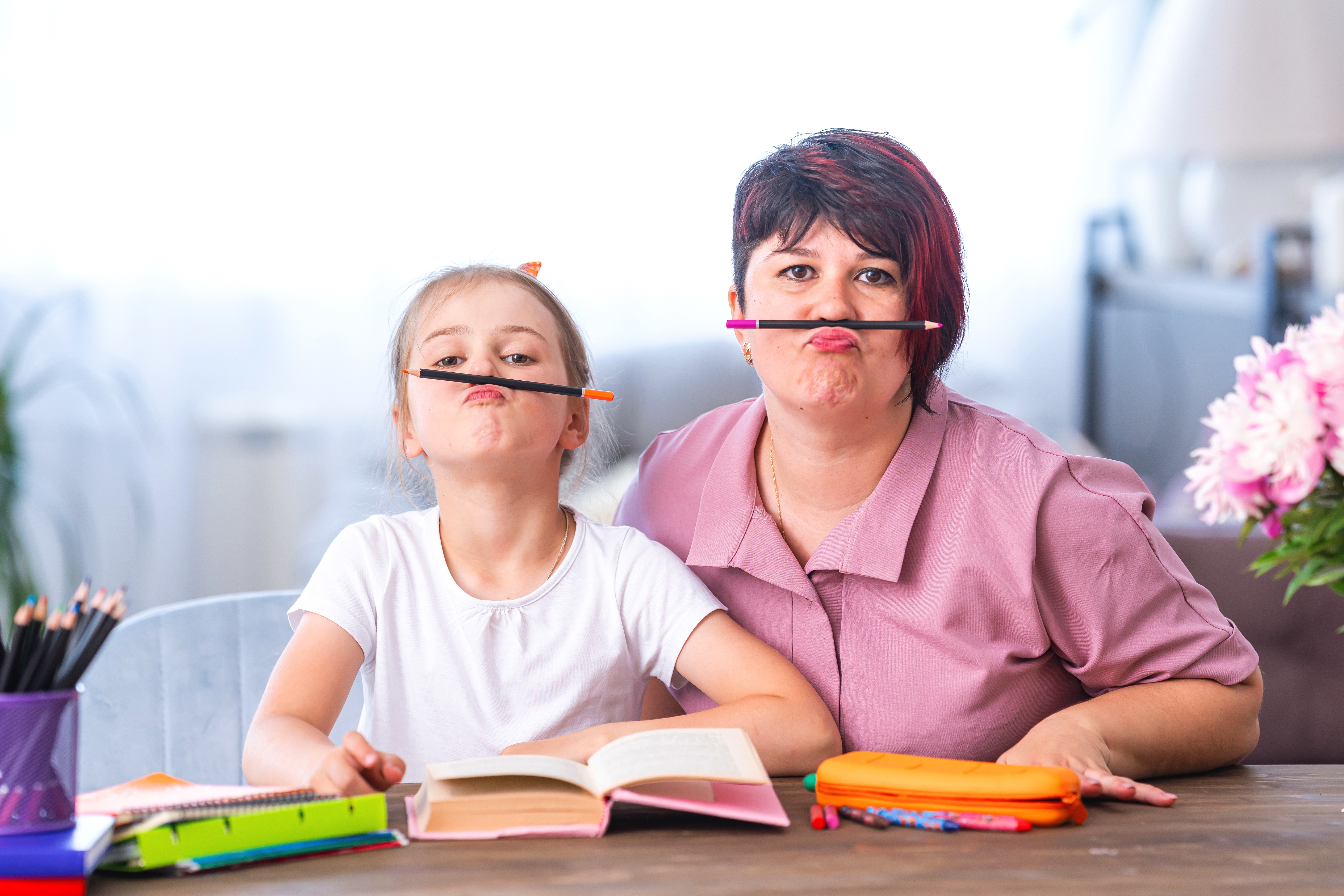 Mom and daughter being silly sitting at a desk working on homework Mom and daughter being silly sitting at a desk working on homework