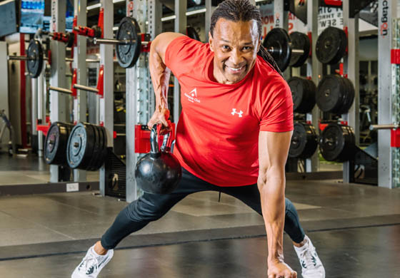 Male membership director - Garth - in a plank with kettlebells, working out in the Strength Gym at the Adelaide Club.