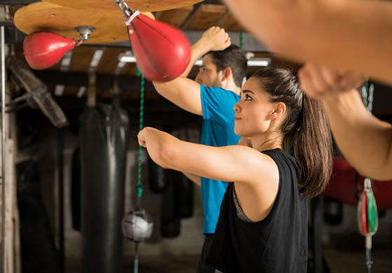 Young men and women hitting the speed bags in a boxing workout class