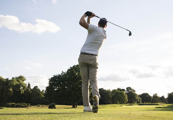 Back of young man after having completed a drive on the golf course