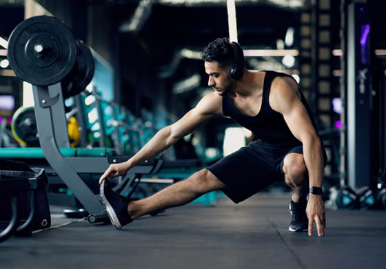 Young, fit man stretching his leg before a workout on the gym floor