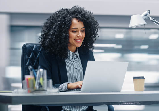 Young, beautiful African American woman working on a laptop at her desk at work