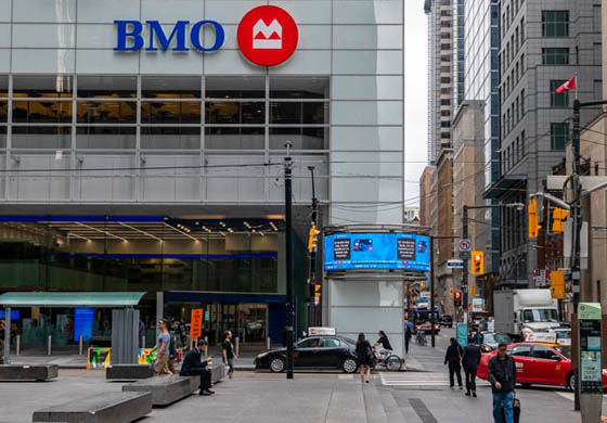 Outside of First Canadian Place in Toronto with large BMO sign up on the building and lots of foot and car traffic on the roads and sidewalks