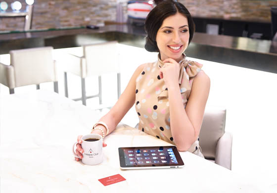 Young, attractive woman sitting in the HUB drinking a coffee in an Adelaide branded mug and her tablet is in front of her on the table